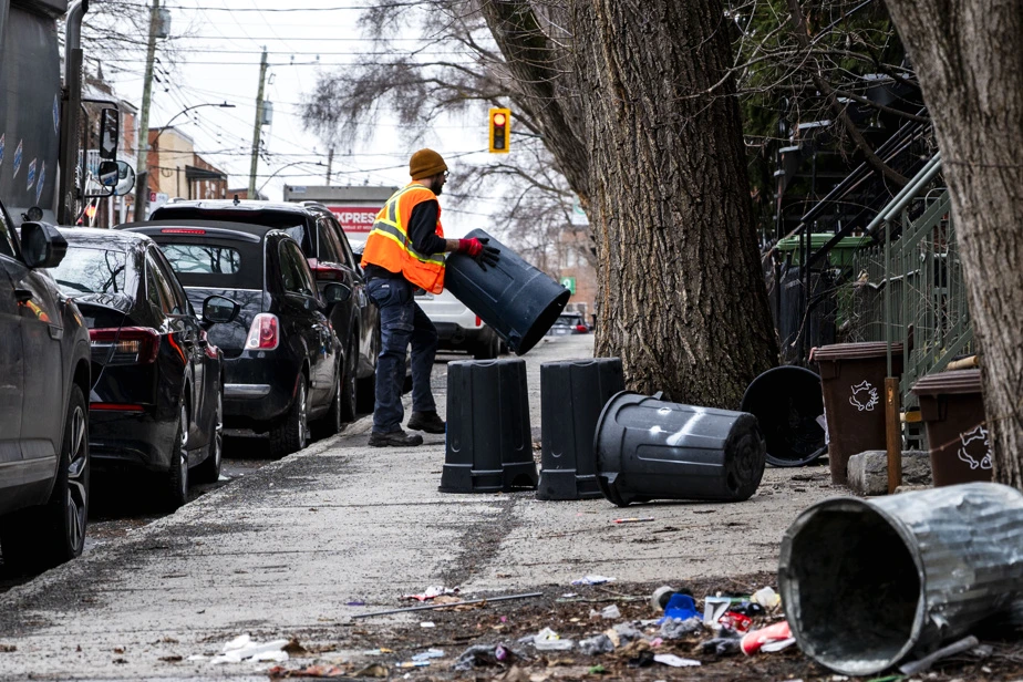Camion de nettoyage de la Ville de Montréal stationné près de sacs-poubelle sur un trottoir urbain