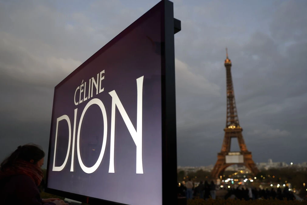 Céline Dion sur scène à Paris, micro à la main, devant un public et des lumières de concert