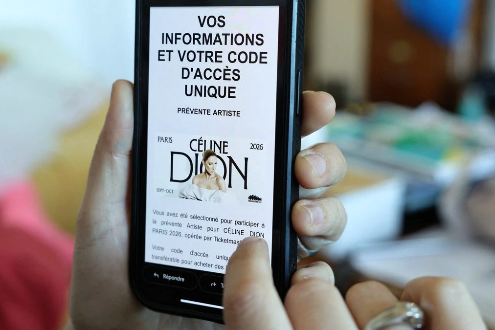 Céline Dion sur scène à Paris, micro en main, sous des projecteurs, devant une foule de fans en concert