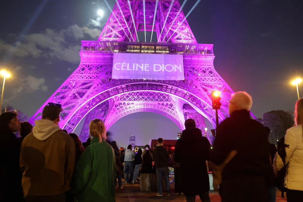 Céline Dion sur scène à Paris, micro en main, sous des projecteurs, devant une foule en concert