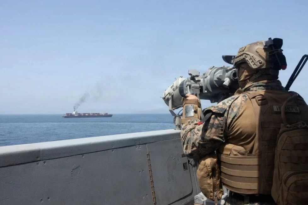 Deux navires dans le détroit d’Ormuz, silhouettes sur mer sombre, avec fumée et éclats au loin