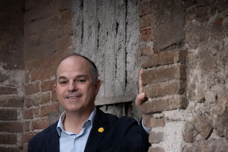 Dirigeants de Junts en conférence de presse, micros devant eux, drapeaux catalans en arrière-plan