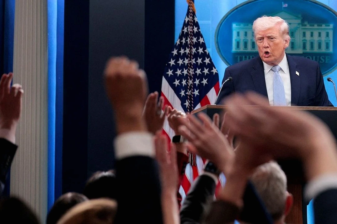 Donald Trump devant des drapeaux américains, micro à la main, lors d’une déclaration à la presse