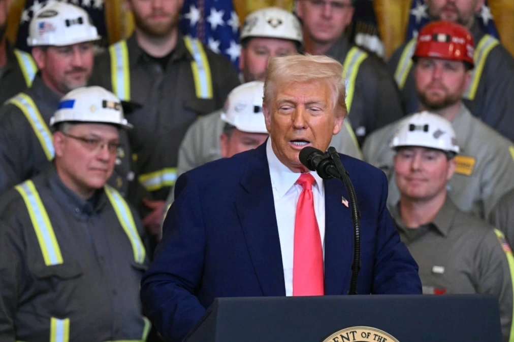 Donald Trump devant des drapeaux américains, parlant au pupitre lors d’un discours officiel.