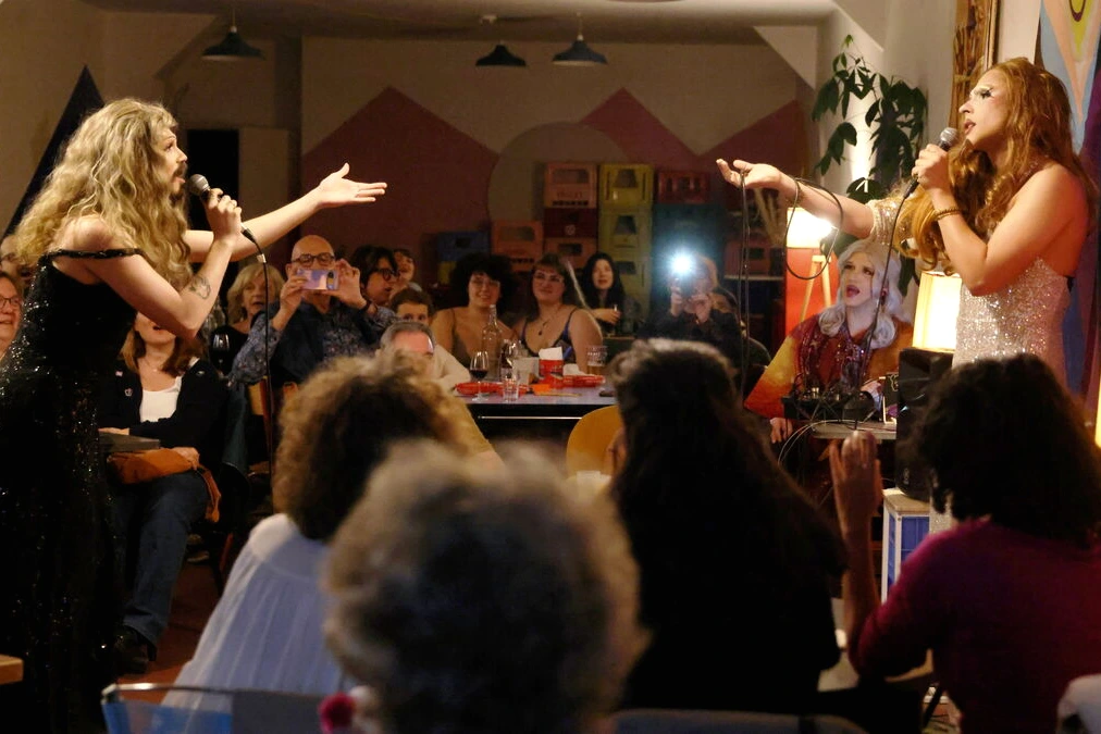 Drag-queens en tenues scintillantes sur scène, devant un public en banlieue, après Paris