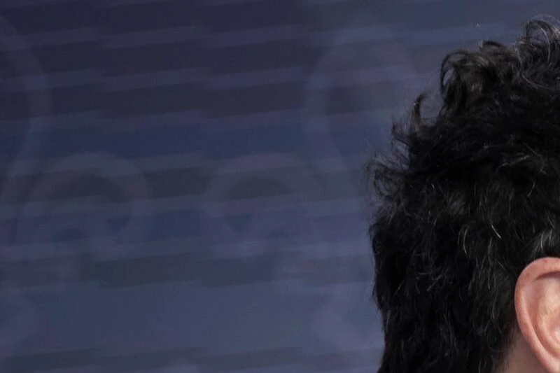 Drainville en gros plan devant des micros, avec le logo de la CAQ en arrière-plan.