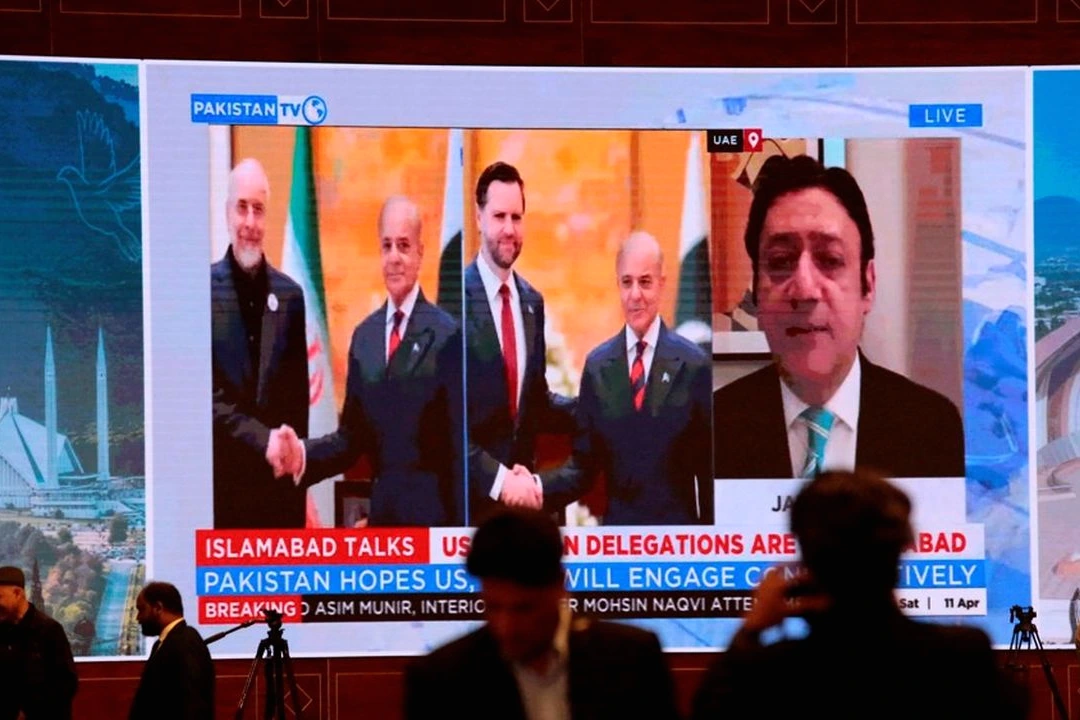 Drapeaux des États-Unis, du Pakistan et de l’Iran alignés devant une table de négociation avec microphones