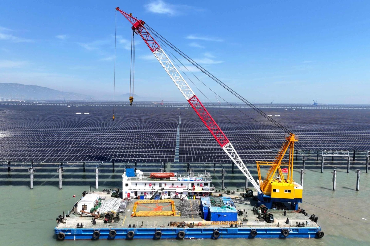Éoliennes et panneaux solaires au premier plan, centrale au charbon en arrière-plan sous un ciel gris