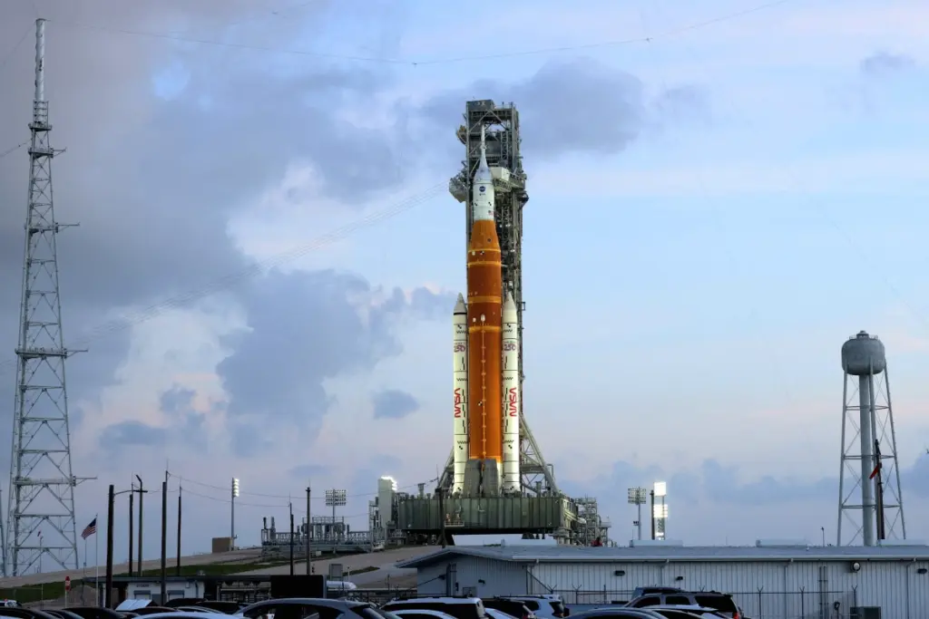 Fusée Artemis II décollant de nuit, traînée de flammes et de fumée, avec drapeau espagnol en surimpression