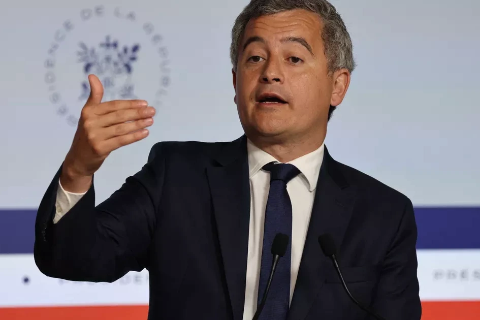 Gérald Darmanin au pupitre, micro devant lui, devant une rangée d’avocats en robe noire dans une salle.