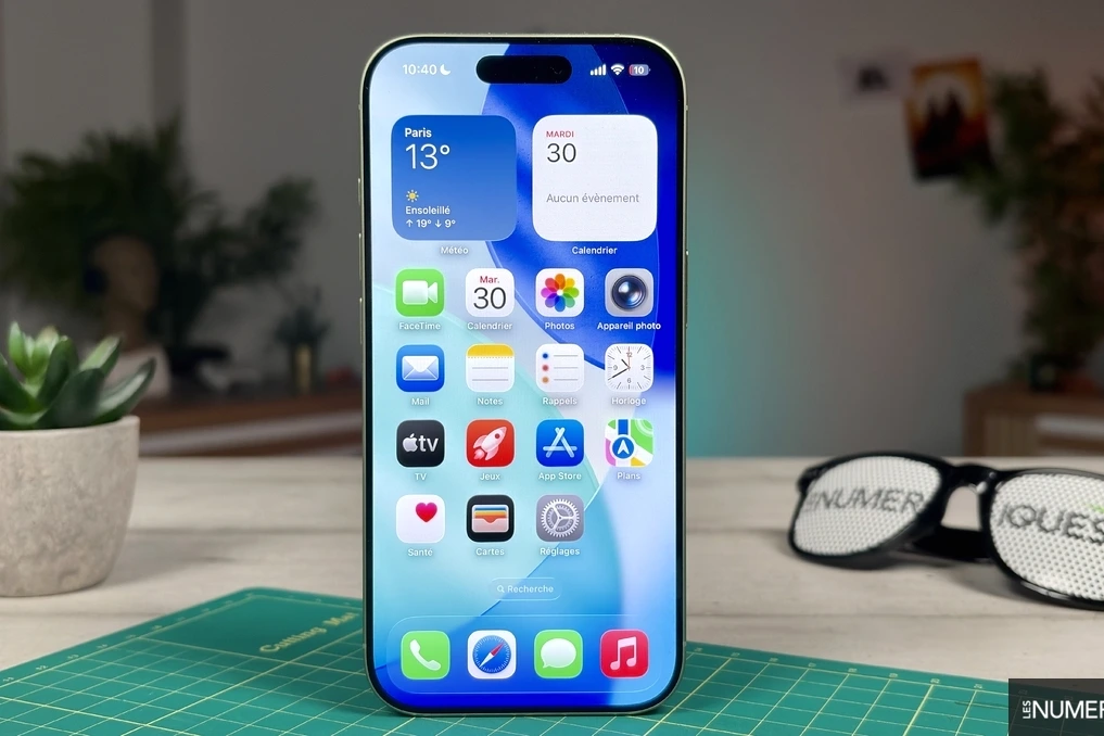 Gros plan d’un iPhone Apple avec écran allumé, posé sur une table, à côté d’un iPhone plus récent.