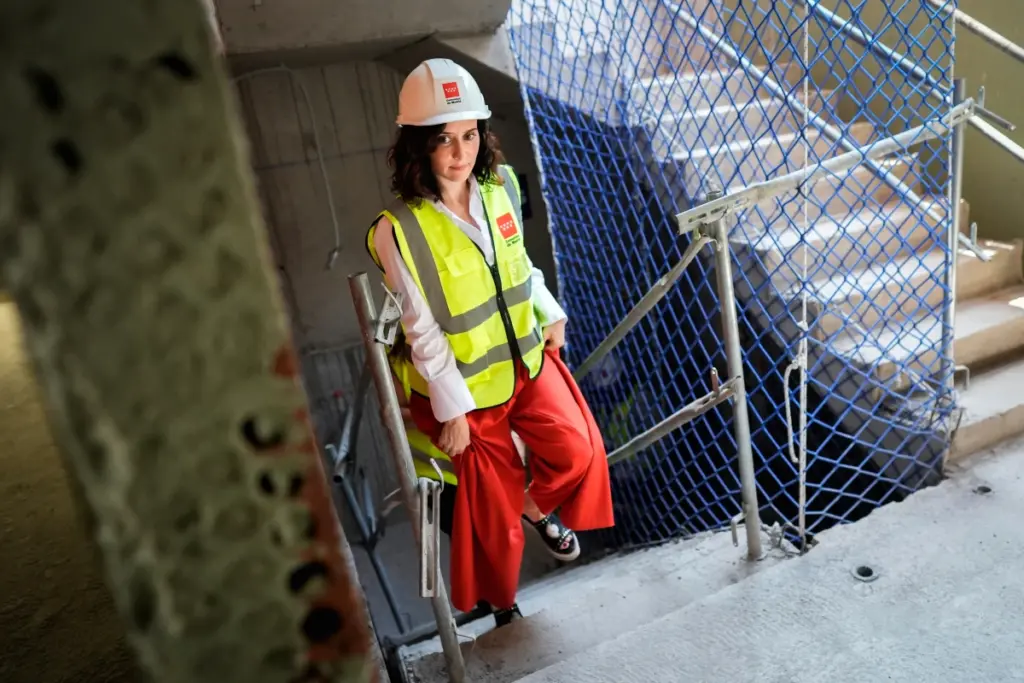 Isabel Díaz Ayuso et Pedro Sánchez se serrant la main devant des drapeaux, lors d’une réunion sur le plan logement.