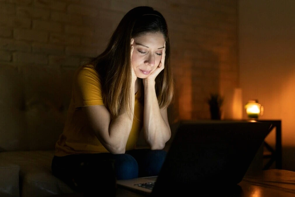 Jeune femme tenant un téléphone affichant ChatGPT, visage contrarié, petit ami flou en arrière-plan