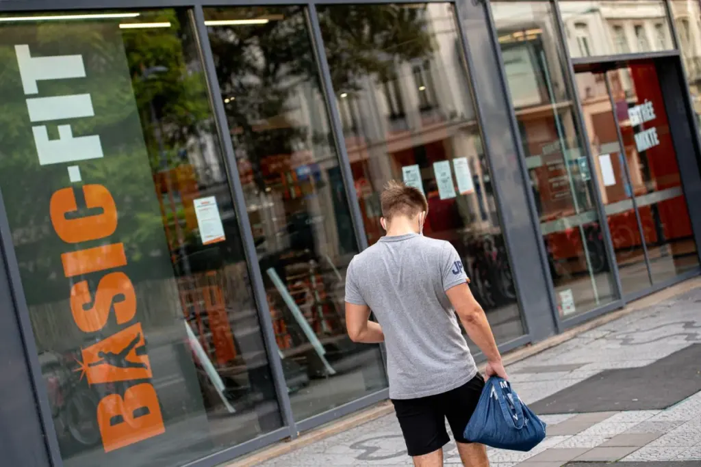 Logo Basic-Fit sur un écran d’ordinateur, avec une alerte de fuite de données et des chiffres en arrière-plan