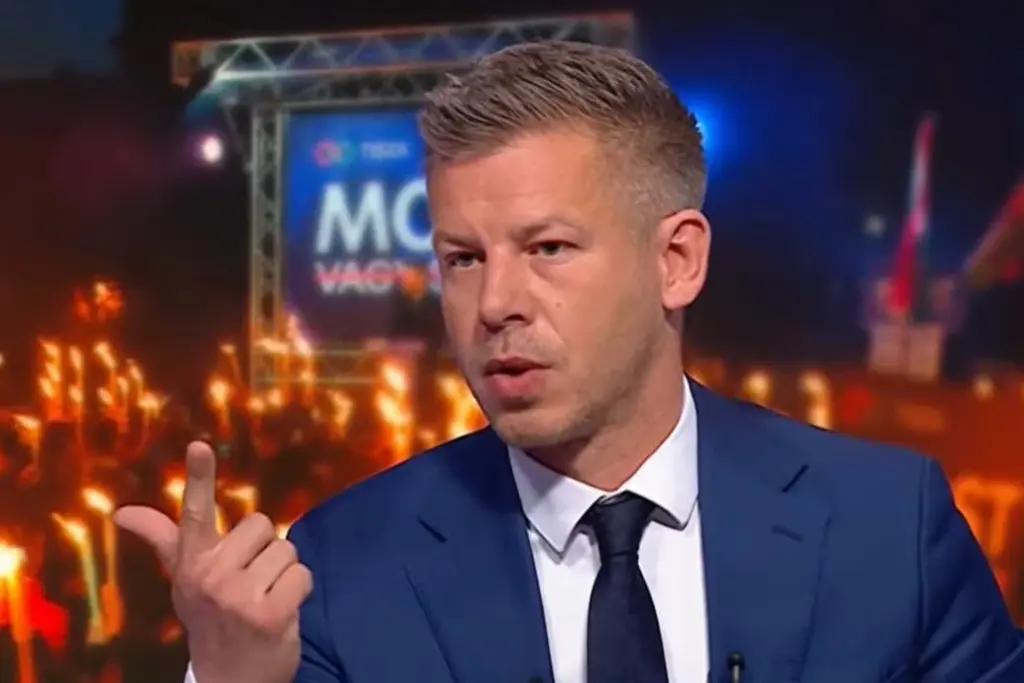 Logo de Magyar sur fond de drapeau hongrois, avec microphones et caméras devant un bâtiment public à Budapest