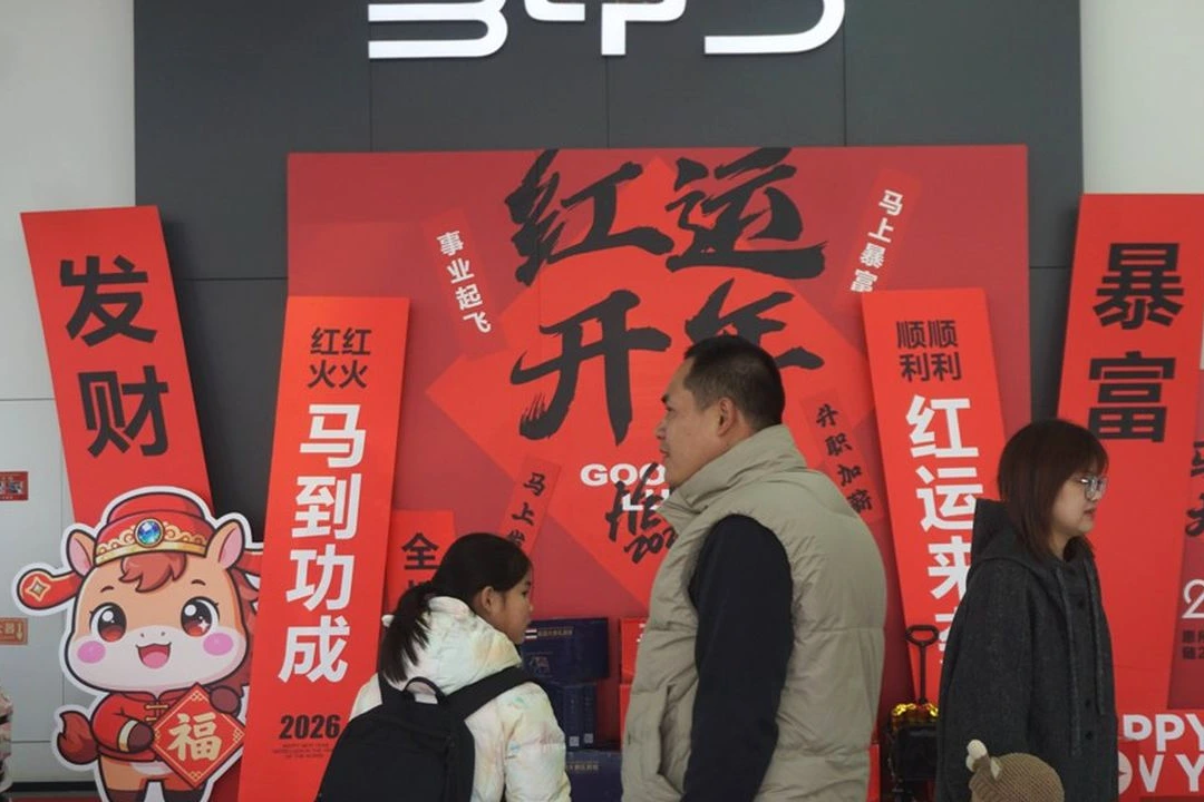 Logo Tesla sur une voiture électrique, avec en arrière-plan un panneau BYD dans une concession en Europe