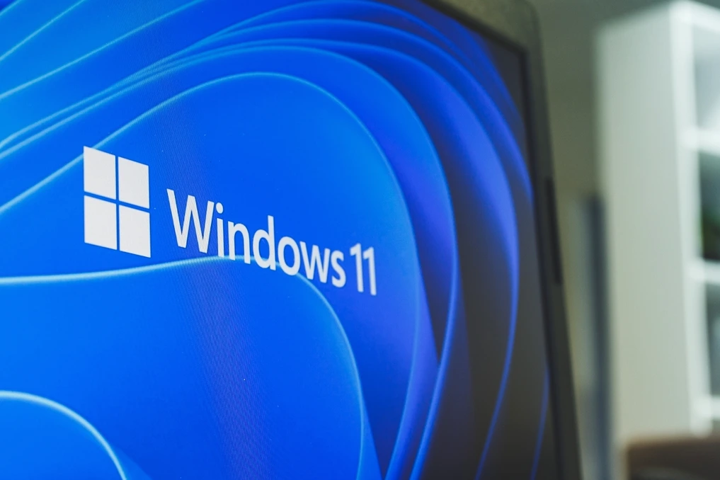 Logo Windows 11 sur écran d’ordinateur portable, avec icône de redémarrage et mention « mises à jour » en arrière-plan