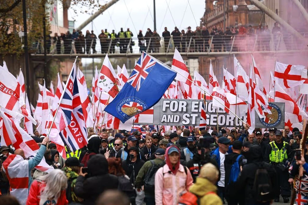 Manifestants et contre-manifestants rassemblés à Manchester, banderoles et policiers visibles dans la foule