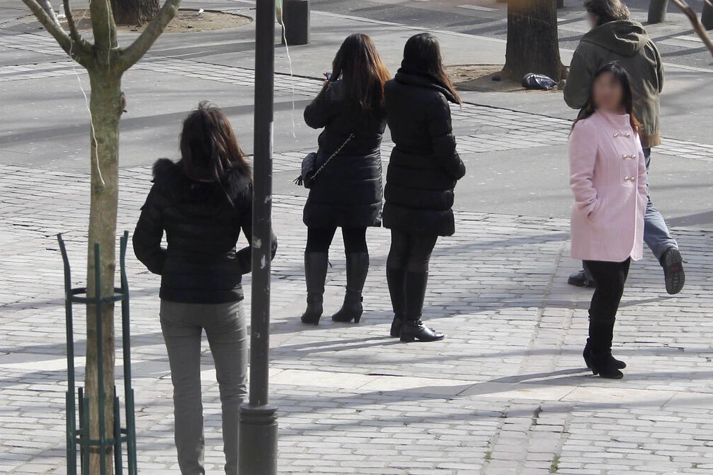 Marcheuses de Belleville marchant sur un trottoir à Paris, de nuit, sous des lampadaires et néons