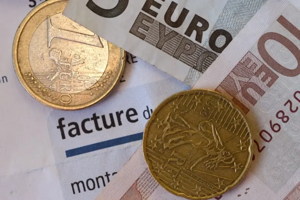 Martine, aide-soignante, en blouse blanche dans un couloir d’hôpital, regard sérieux vers l’objectif.