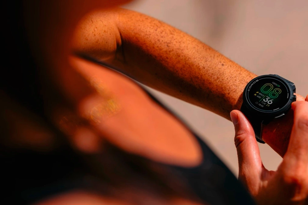 Montre Coros affichant des métriques de course sur l’écran, posée près d’un smartphone avec mise à jour ouverte