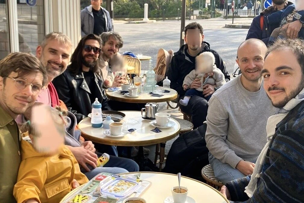 Pères assis en cercle dans un club de papas à Paris, discutant autour de cafés dans une salle lumineuse