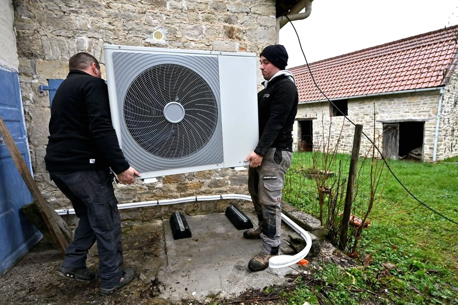 Pompe à chaleur installée sur la façade d’une maison, technicien en gilet, document de leasing social en main