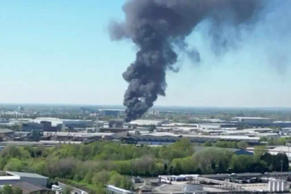 Pompiers luttant contre un grand incendie à Manchester, flammes et épaisse fumée au-dessus des bâtiments