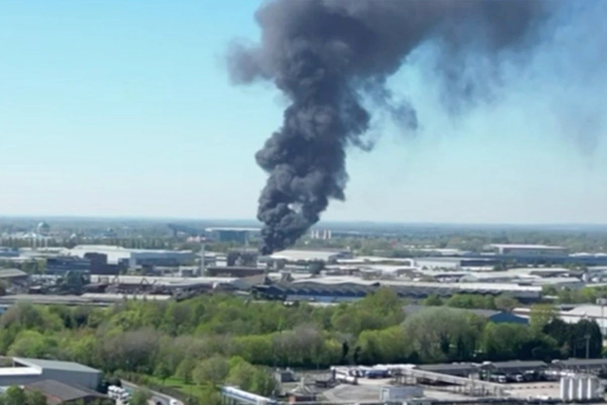 Pompiers luttant contre un grand incendie à Manchester, flammes et épaisse fumée au-dessus des bâtiments