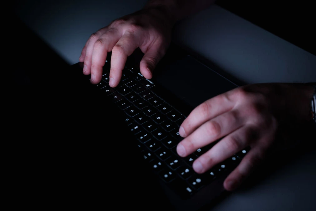 Portrait d’un patron de la French Tech en costume, devant un fond flou avec logos de startups