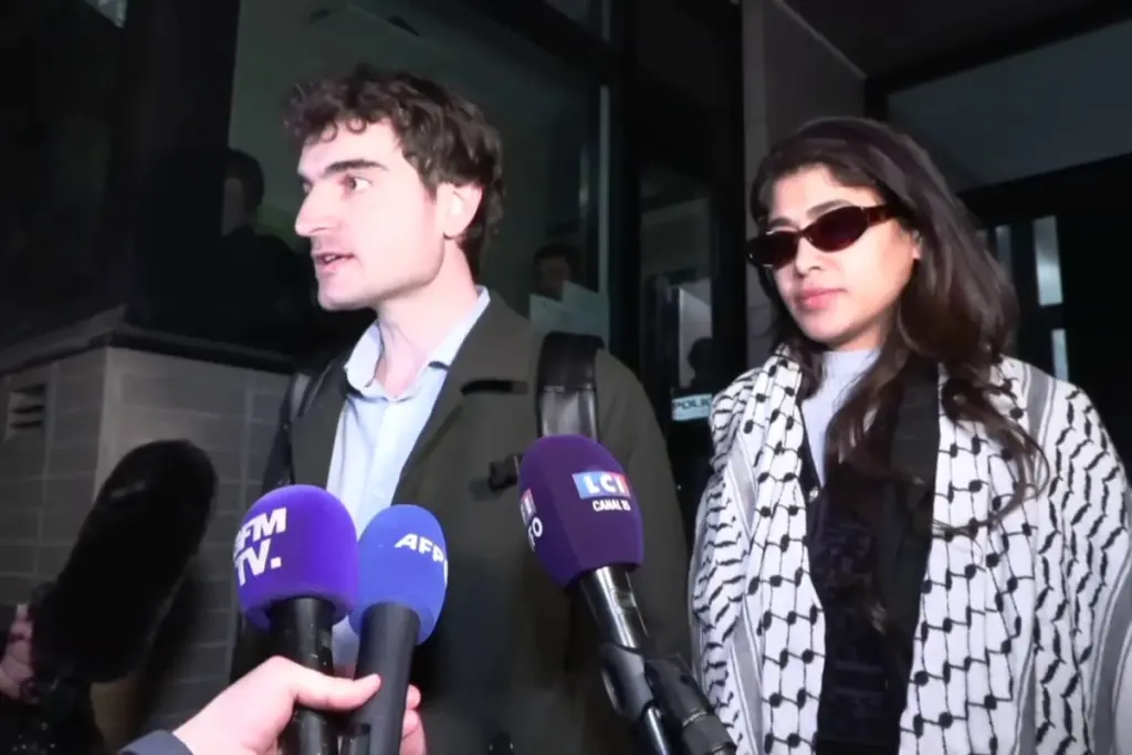 Rima Hassan devant un bâtiment judiciaire, entourée de journalistes et de micros, à la sortie de garde à vue