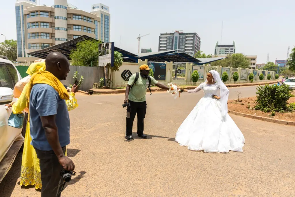 Rue animée de Bamako avec passants et motos, soldats en uniforme visibles près d’un carrefour.