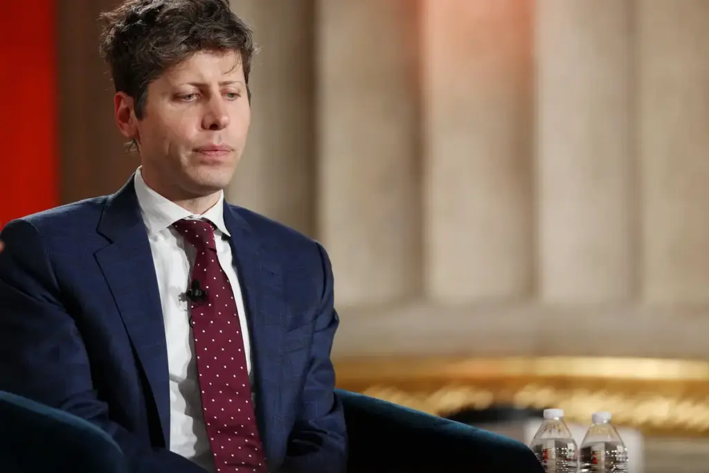 Sam Altman devant un micro, en conférence de presse, avec le logo ChatGPT en arrière-plan