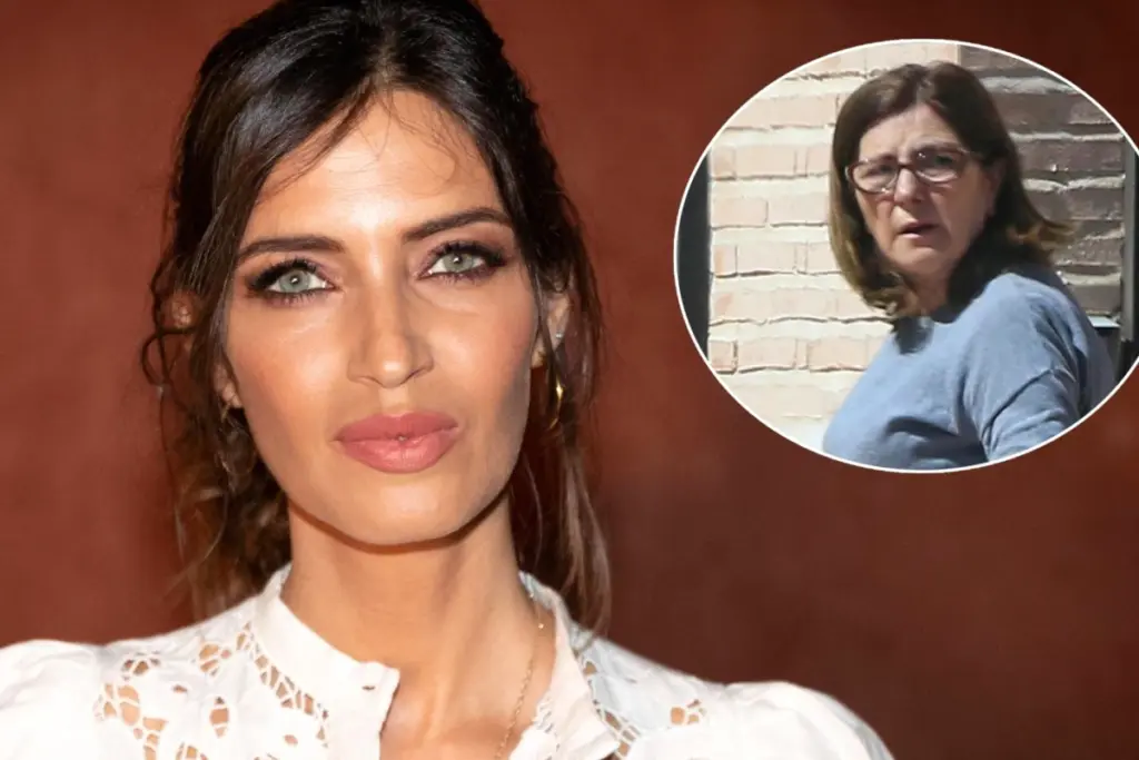 Sara Carbonero posant devant un mur clair, regard sérieux, cheveux bruns lâchés, en tenue sombre.