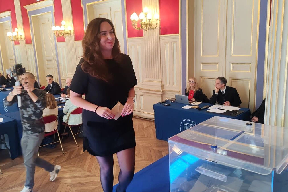 Sarah Knafo posant devant un bâtiment parisien, micro à la main, lors d’un déplacement à Paris 16e