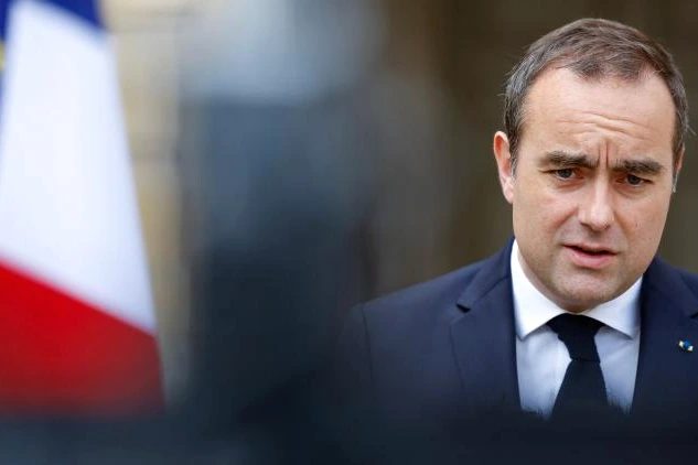 Sébastien Lecornu en costume, parlant à des journalistes devant un bâtiment officiel, microphones tendus.