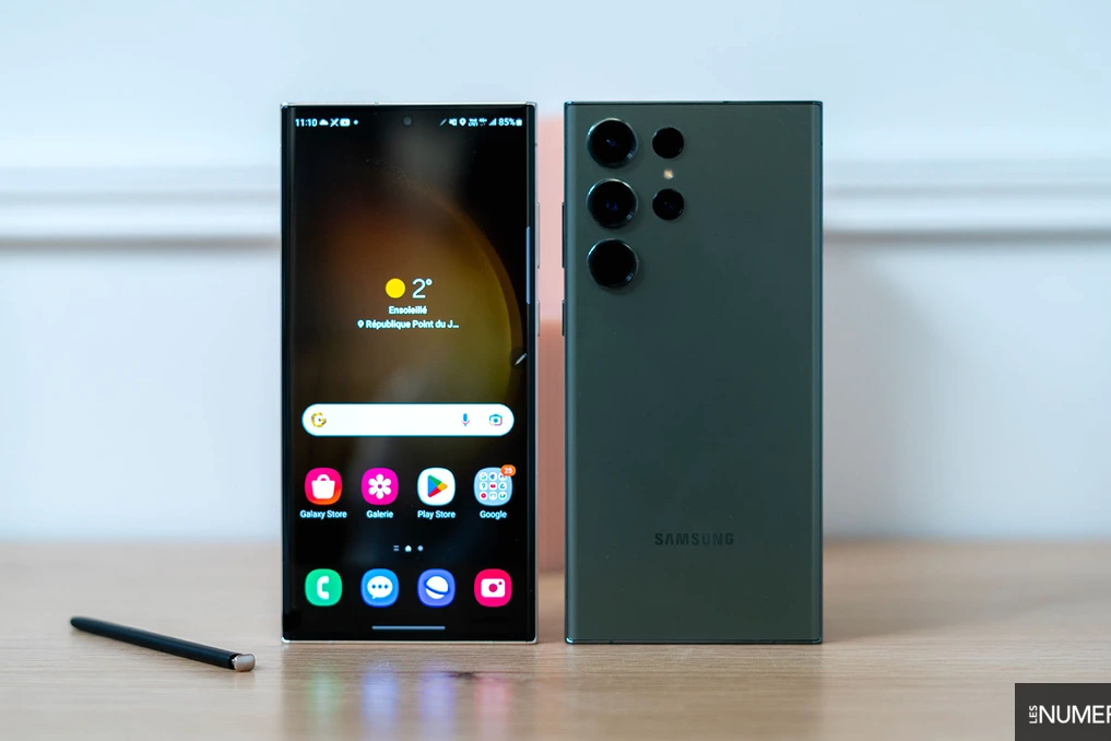 Smartphone Samsung Galaxy S23 affichant l’interface One UI 8.5 sur l’écran, posé sur un fond sombre