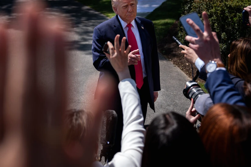 Trump assis à table lors d’un dîner avec des journalistes, échangeant des propos dans une salle éclairée.