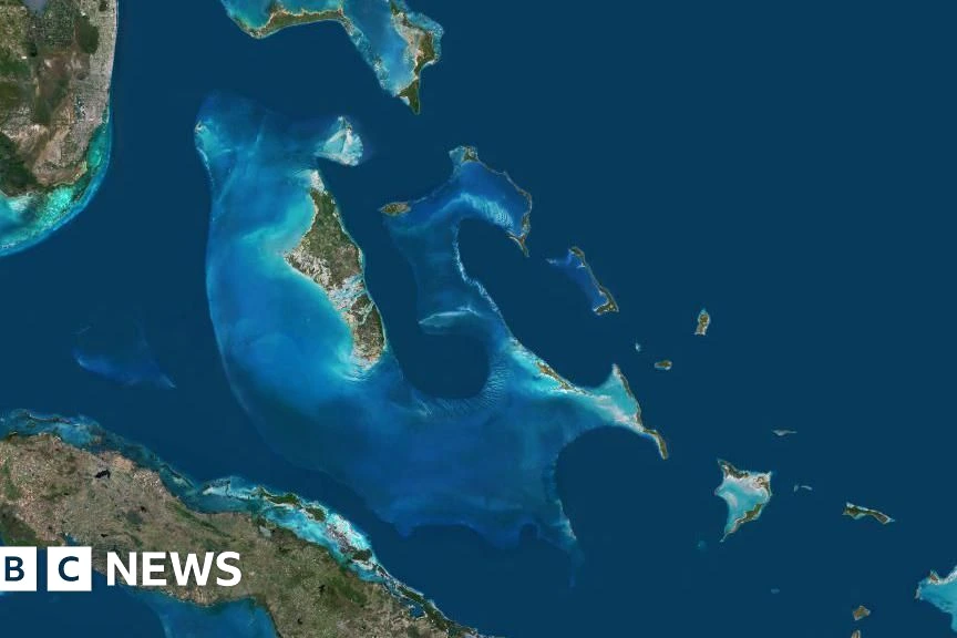 Un Américain menotté escorté par des policiers, avec une femme du Michigan recherchée en arrière-plan, aux Bahamas