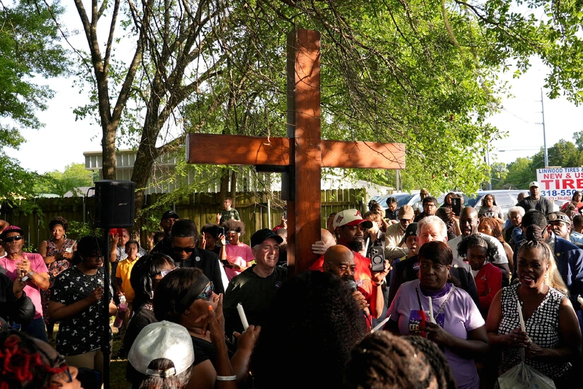 Un homme inculpé en Louisiane menotté, escorté par des policiers devant un bâtiment judiciaire.