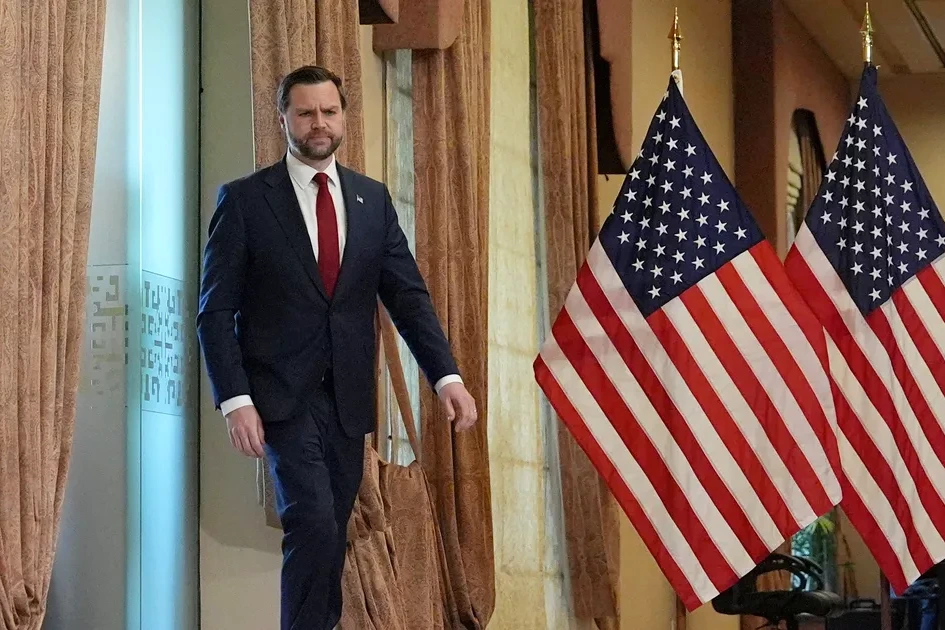 Vance descend d’un avion sur le tarmac au Pakistan, entouré d’agents de sécurité et de drapeaux.