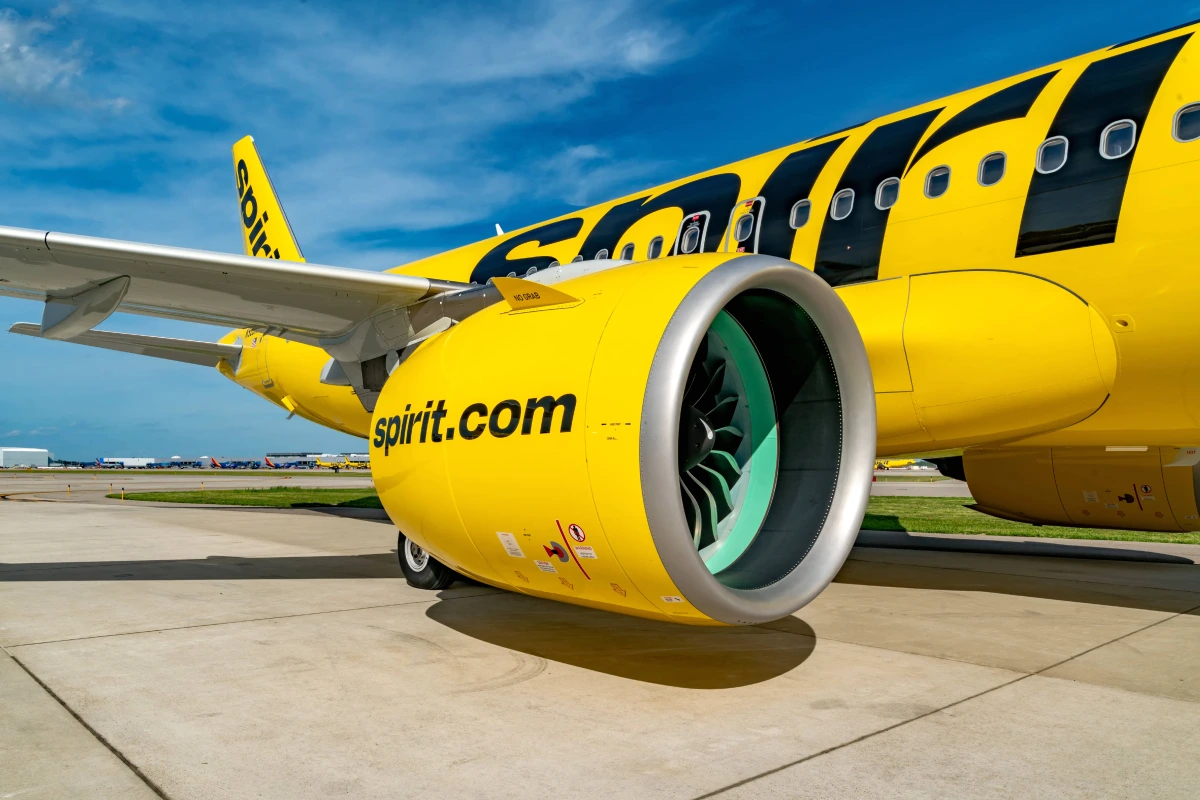 Avion Spirit Airlines jaune sur le tarmac, avec passagers et comptoir d’enregistrement en arrière-plan