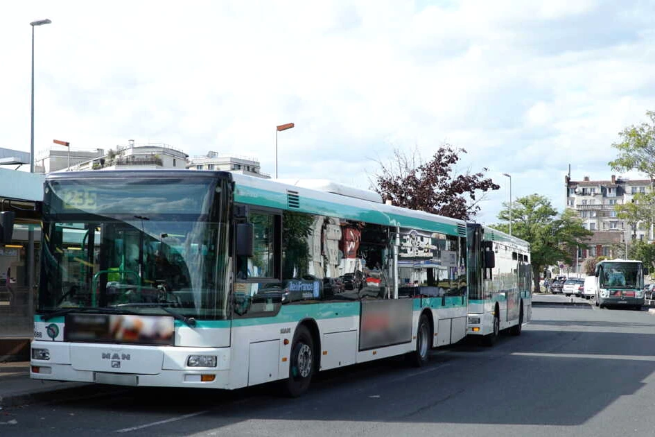 Bus urbain sur une ligne en ville, arrêt de bus et passagers visibles, illustrant la concurrence sur les lignes