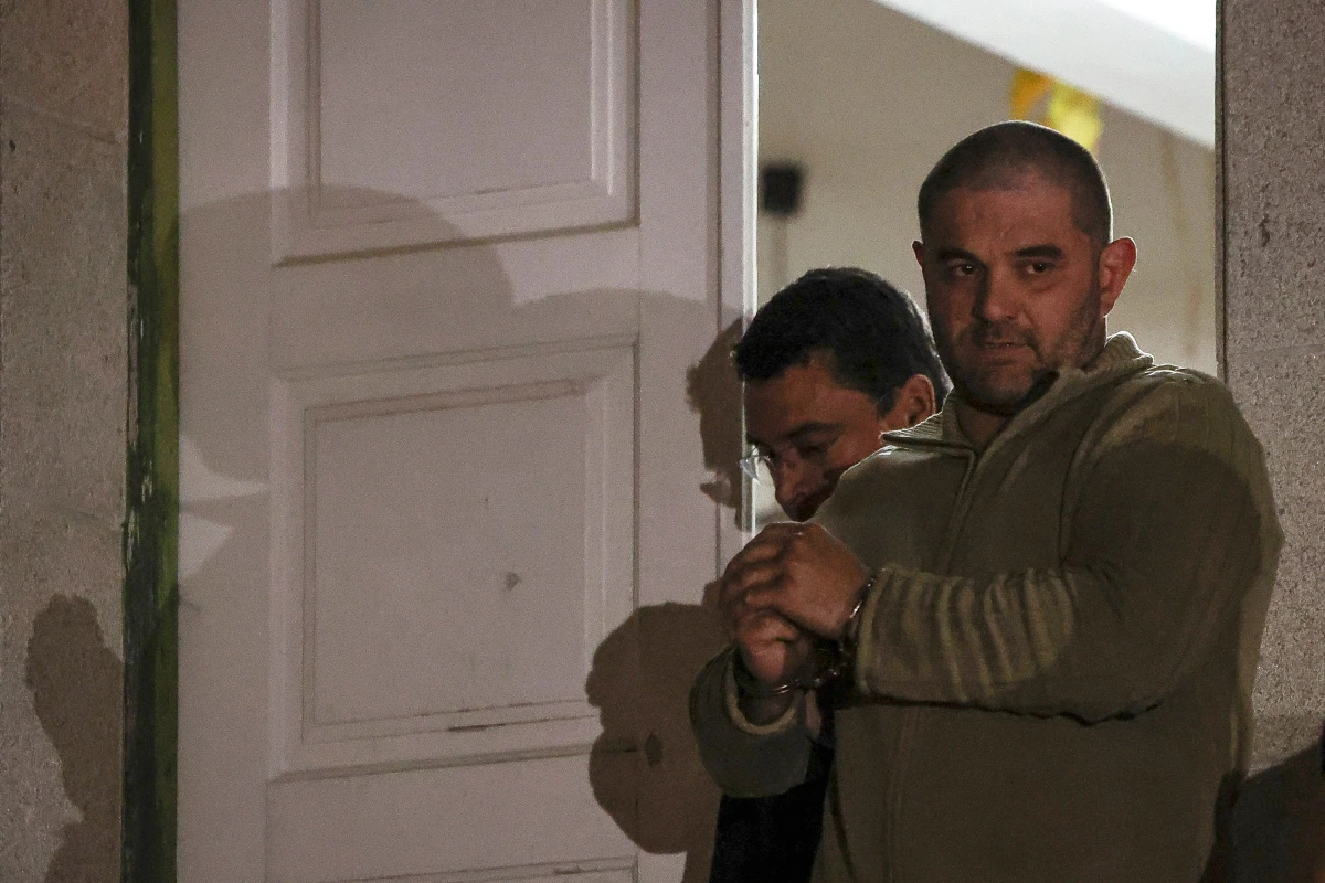 Cédric Prizzon escorté par des gendarmes, menotté, entrant dans un bâtiment judiciaire en Aveyron