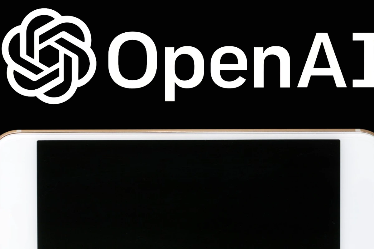 Chercheurs devant un tableau rempli d’équations, utilisant l’IA d’OpenAI sur un ordinateur portable.