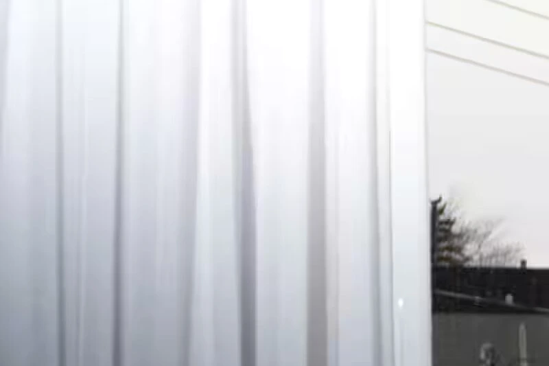 Détenu assigné à domicile, bracelet électronique à la cheville, assis seul dans un salon sombre.