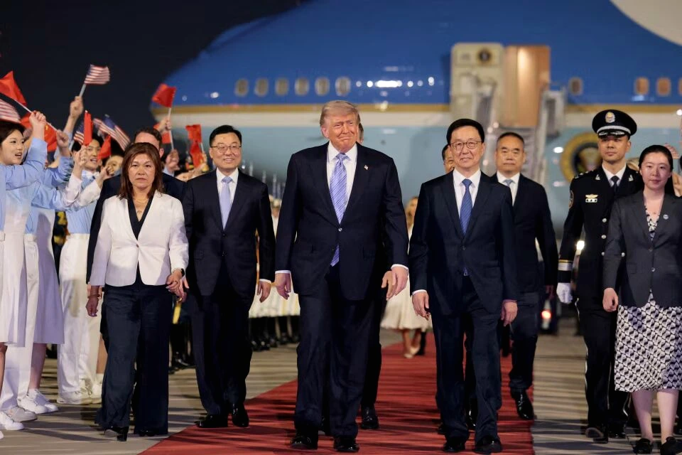 Donald Trump descend d’un avion à son arrivée en Chine, entouré de gardes et de drapeaux chinois