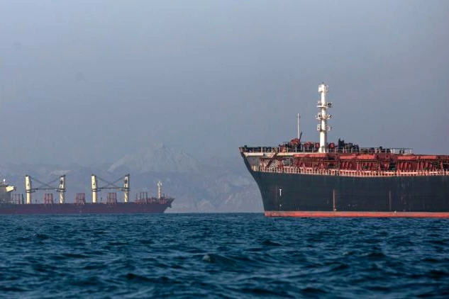 Drapeau iranien flottant devant un navire près du détroit d’Ormuz, au coucher du soleil