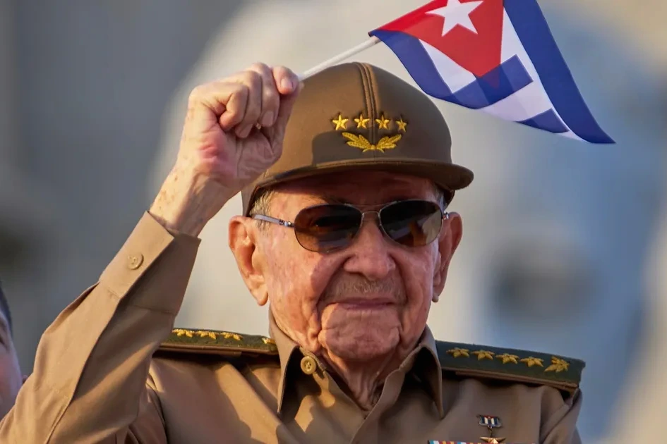 Drapeaux des États-Unis et de Cuba côte à côte, avec Donald Trump en arrière-plan lors d’un discours.