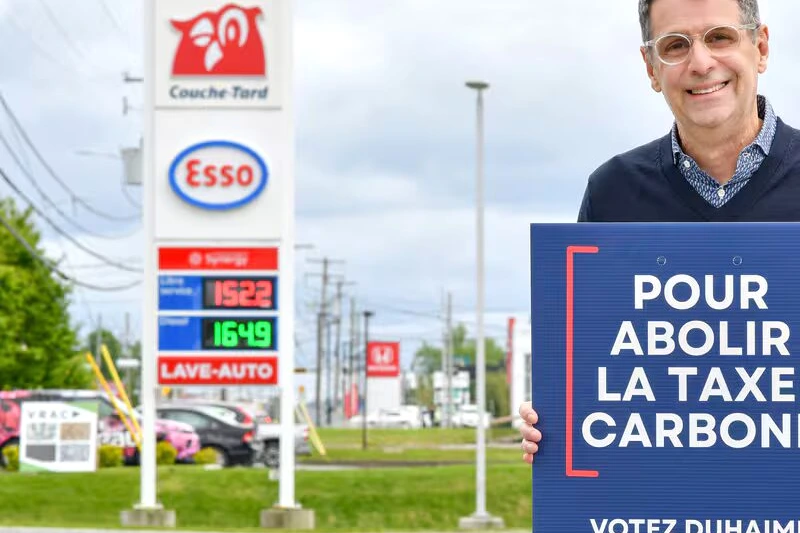 Éric Duhaime au pupitre lors d’une conférence de presse, micros devant lui et drapeau du Québec en arrière-plan